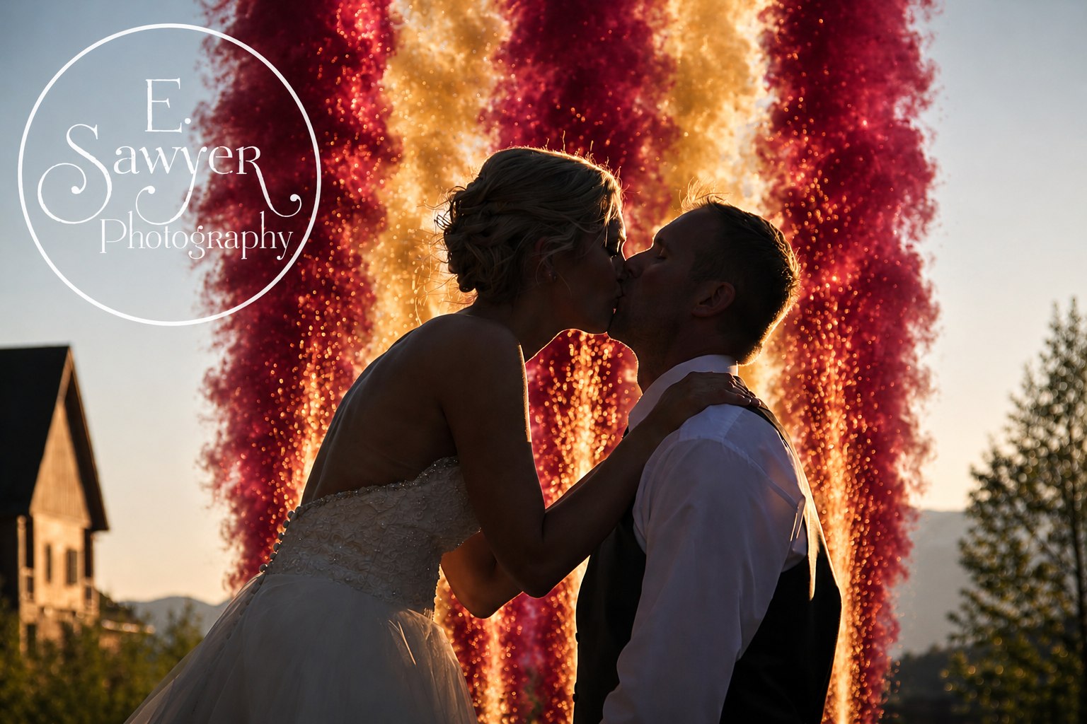 Red and gold fireworks gerb wall behind a kissing bride and groom Bride and groom kissing in front of a wall of red and gold fireworks gerbs at their wedding reception